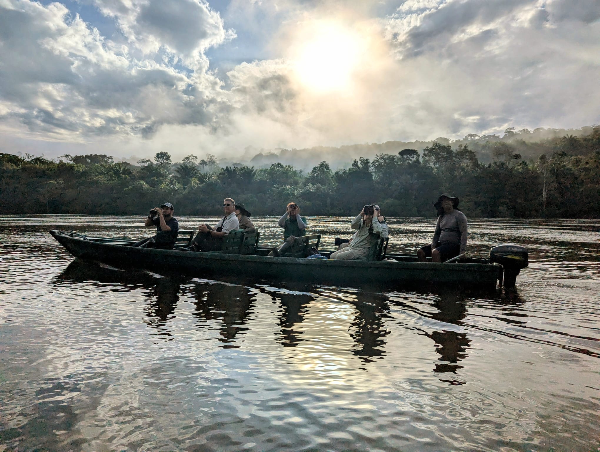 Naturalist guides and guests birdwatching from a canoe at sunrise on the Amazon