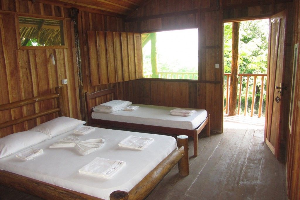 Rustic lodge room at the Amazon eco lodge — wooden walls, balcony overlooking the forest