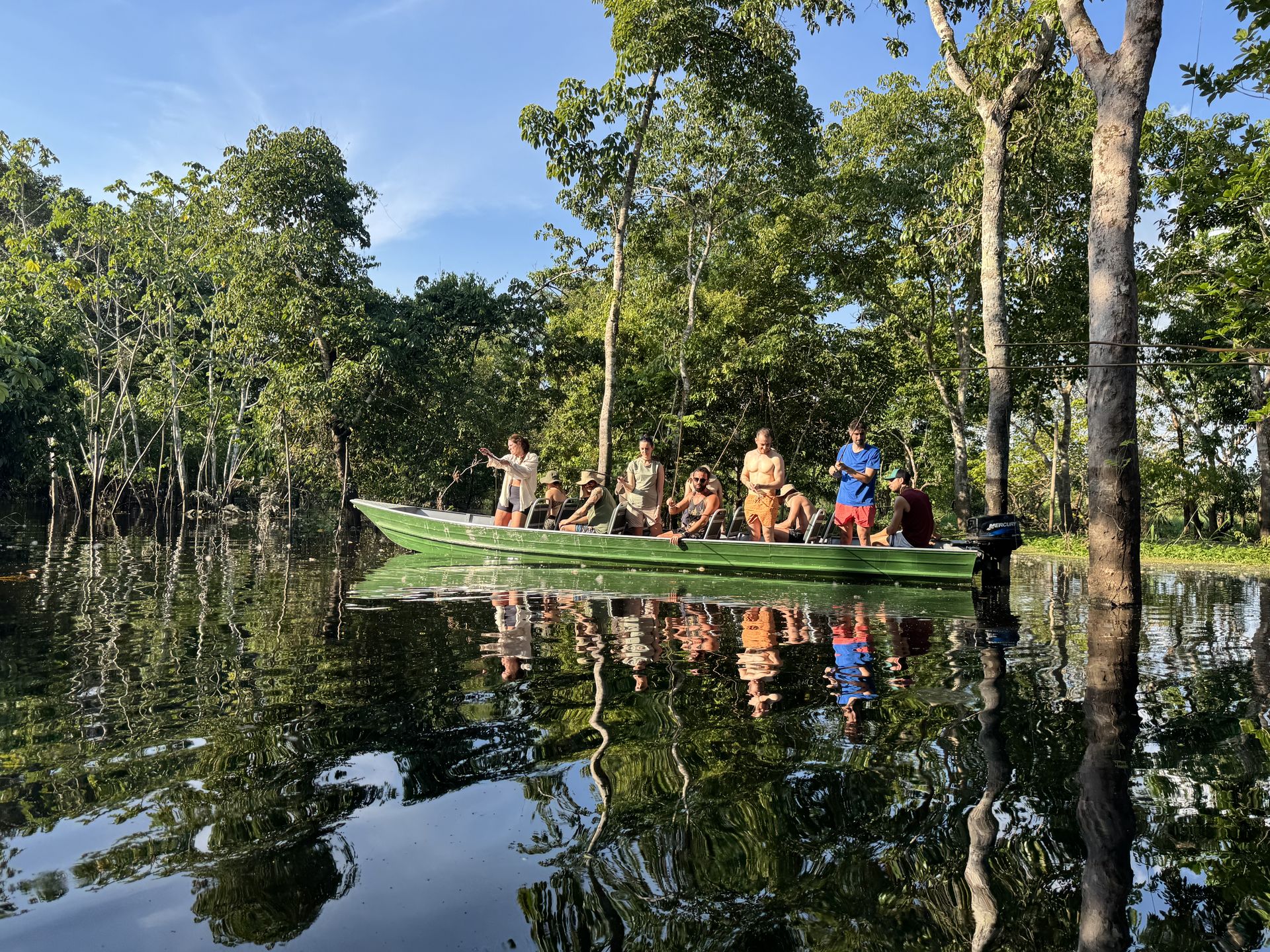 Group of travellers on a green expedition boat navigating the flooded igapó forest, Rio Negro, Amazonas